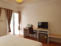 a bedroom with a desk with a television and a bed at Nice Sea Resort in Srithanu
