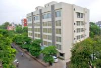 Un edificio blanco con árboles delante. en Shantai Hotel, en Pune