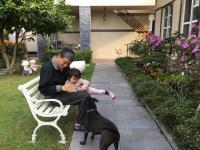 a man sitting on a bench with a child and a dog at Champs Yazuh B&amp;B in Jiji