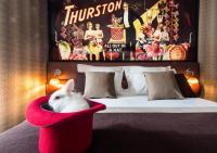 a white rabbit sitting in a red chair next to a bed at Hotel Splendor Elysées in Paris