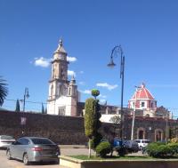 een auto geparkeerd voor een gebouw met een klokkentoren bij Hotel Boutique Yaocalli in San Martín de las Pirámides