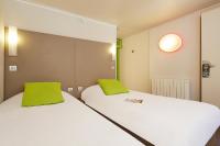 two beds in a small room with green pillows at Campanile Hotel Compiegne in Compiègne