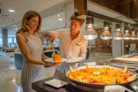 Ein Mann und eine Frau halten Teller mit Essen. in der Unterkunft RH Princesa Hotel & Spa 4* Sup in Benidorm