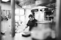 Ein Mann steht in einer Küche und bereitet Essen vor in der Unterkunft Hotel Zirbelstube in Nürnberg