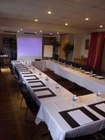 a row of tables in a large room with a screen at Geographotel Paris-Roissy CDG Airport in Le Mesnil-Amelot