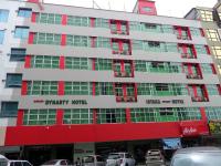un edificio en una ciudad con coches aparcados delante de él en Monaco Dynasty Hotel, en Tawau
