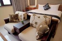 a hotel room with two beds and a chair at 開心居-正市中心電梯民宿-步行東大夜市5分鐘 in Hualien City