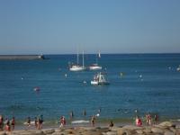 a group of people on a beach with boats in the water at Toki Alai in Saint-Jean-de-Luz