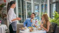 Un hombre y una mujer sentados en una mesa comiendo comida en Hotel RH Royal - Recommend for adults, en Benidorm