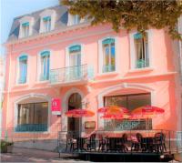 a pink building with tables and umbrellas in front of it at Hôtel De France in Chalabre