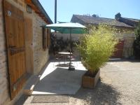 eine Terrasse mit einem Tisch und einem Sonnenschirm in der Unterkunft le gîte de viré in Viré