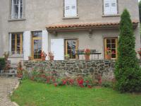 a house with a stone wall and flowers at La Maison de Mireille in Le Puy-en-Velay