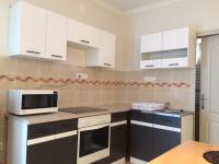 a kitchen with white cabinets and a microwave at Báró Berg Apartman in Kapuvár