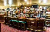a bar with green stools in a room at Korona Hotel in Nyíregyháza