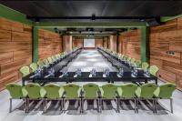 a conference room with a long table and green chairs at IOTA Hotel Tbilisi in Tbilisi City