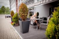 Eine Frau, die an einem Tisch auf einer Terrasse sitzt in der Unterkunft Park Hotel Diament Katowice in Kattowitz