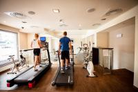 Ein Mann und eine Frau stehen auf einem Laufband in einem Fitnessstudio. in der Unterkunft Park Hotel Diament Katowice in Kattowitz