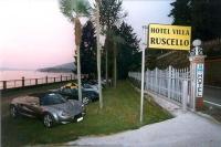 two cars parked next to a hotel with a sign at Hotel Villa Ruscello in Baveno