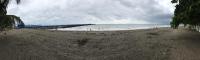 a beach with a pier and people in the water at Hotel Sol Puntarenas in Puntarenas