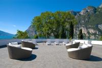 a group of chairs and tables on a patio at Hotel Oasi Wellness &amp; Spa in Riva del Garda