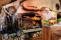 Un hombre parado frente a un horno con un pavo. en Spa Hotel Rich, en Velingrad