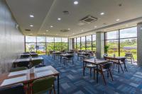 a restaurant with tables and chairs and windows at Hotel Sweet Castle Jeju Hamdeok in Jeju