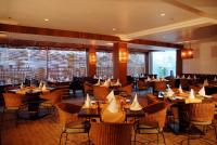 a restaurant with tables and chairs and windows at Hotel Palace Heights in New Delhi