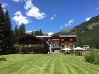 a large building with a grass field in front of it at Le Rocher Hotel in Champoluc