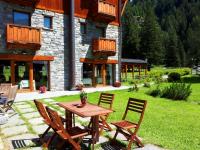a wooden table and chairs in front of a building at Le Rocher Hotel in Champoluc