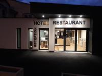 a hotel restaurant with its doors open at night at La Godinière in Cholet