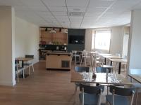 a dining room with tables and chairs and a kitchen at La Godinière in Cholet