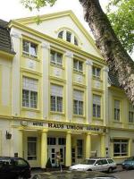 un edificio amarillo con un coche blanco aparcado delante de él en Hotel Haus Union, en Oberhausen