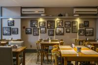 クリシウマにあるTri Hotel Premium Criciúmaの壁に絵画が飾られたテーブルと椅子のあるレストラン