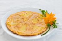 una frittella su un piatto bianco con un fiore giallo di Hanoi Stella Hotel a Hanoi