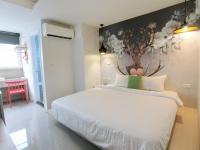 a bedroom with a white bed with a painting on the wall at S&amp;E Hotel in Tainan