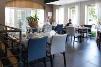 um grupo de pessoas sentadas às mesas de um restaurante em Koru Hôtel & Private Wellness em Autre-Église