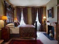 a bedroom with a large bed with curtains and a fireplace at The Rookery in London