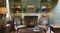 a living room with a fireplace with two chairs and a table at The Rookery in London
