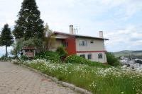 a house on a hill with flowers in front of it at Pousada Colina Da Neve in São Joaquim