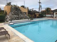 a swimming pool in a resort with a stone wall at Pousada Casa do Catavento in Búzios