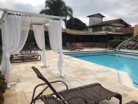 a pool with a gazebo and chairs next to aophethritisthritis at Pousada Casa do Catavento in Búzios