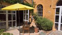 a table with a yellow umbrella and two chairs at Le Clos des Pierres Dorées in Theizé