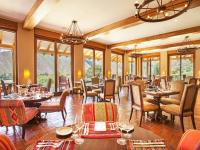 Un restaurante con mesas, sillas y ventanas. en Inkaterra Hacienda Urubamba, en Urubamba