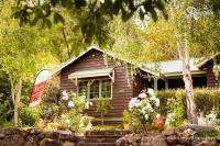 a small wooden house with flowers in front of it at Riverglen Chalets in Margaret River Town