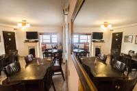 Un comedor con mesas y sillas de madera. en Pensiunea Carmen, en Ranca