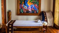 a bed in a room with a painting on the wall at Qunci Villas Resort in Senggigi