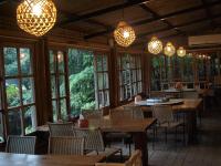 Un restaurante con mesas y sillas de madera y ventanas. en Zhou Ye Cottage, en Sanyi
