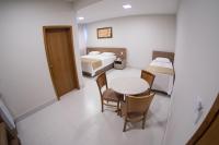 una habitación con dos camas y una mesa y sillas en Hotel Royal, en Salinas