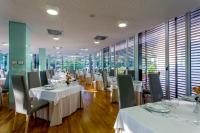 a restaurant with white tables and chairs and windows at Hotel Valle del Jerte in Jerte