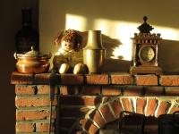 a brick fireplace with a clock and a stuffed bear on it at La Quitapenas in Ronse